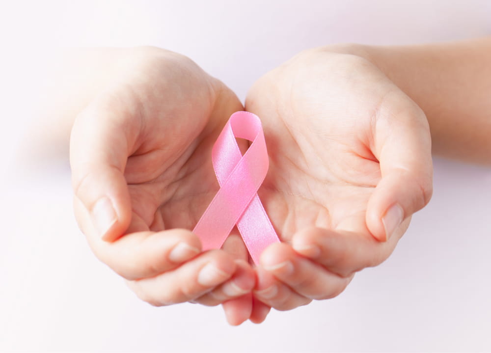 Cupped hands holding a pink ribbon